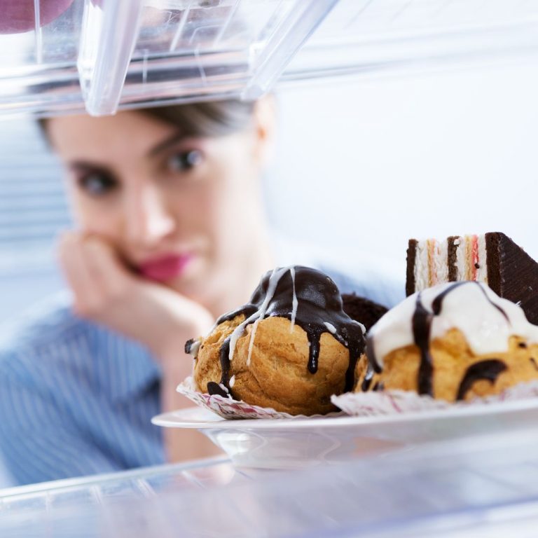 A girl looks into the fridge at some sweet treats.