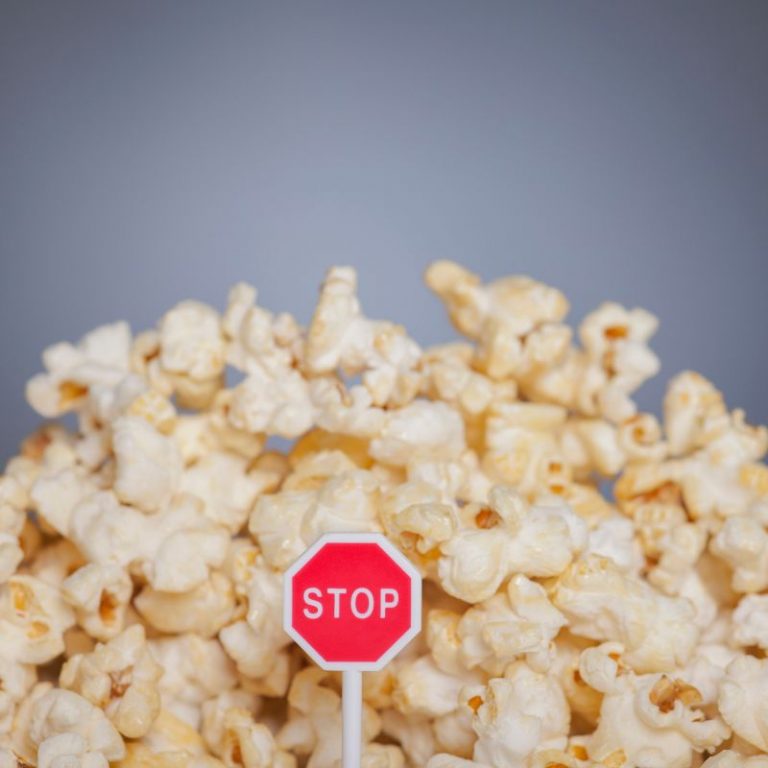 Popcorn with a tiny STOP sign placed in, preventing emotional overeating.